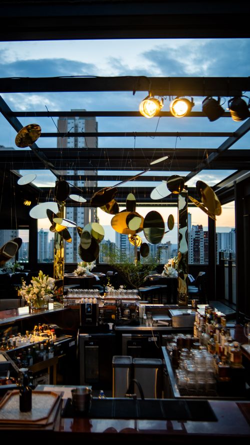 Free Luxurious rooftop bar with elegant golden decor and cityscape view at dusk. Stock Photo