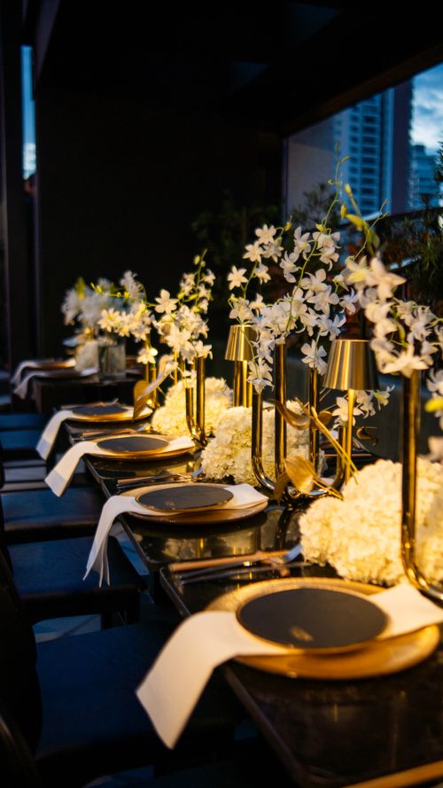 Free A sophisticated table setting featuring gold accents, white flowers, and ambient lighting for a luxury event. Stock Photo