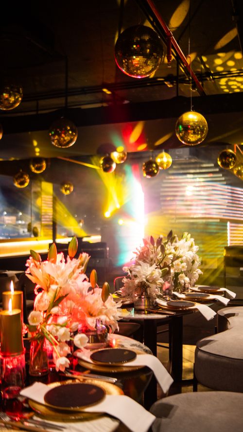 Free Luxurious dining table set under golden disco balls with vibrant lighting in a stylish venue. Stock Photo