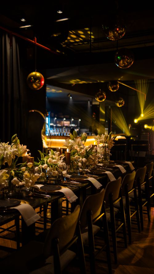 Free Chic event space featuring elegant table setup, moody lighting, and lush florals. Stock Photo