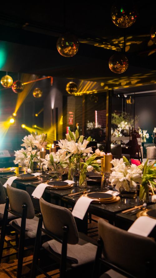 Free A beautifully set dinner table with floral arrangements and golden lighting, perfect for a party. Stock Photo
