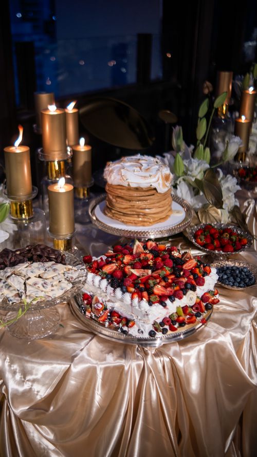 Free Elegant dessert table with layered cakes and fresh berries, adorned with golden candles. Stock Photo