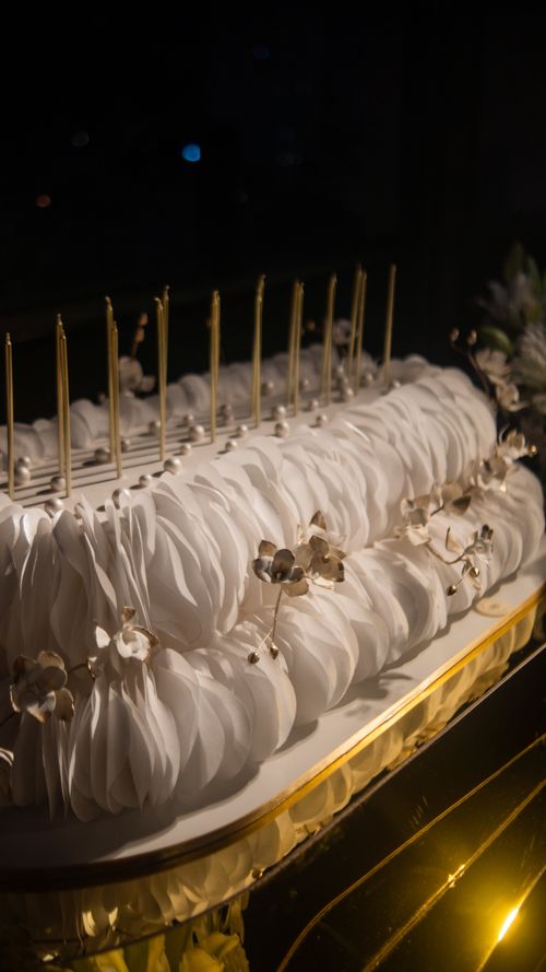Free Luxurious white cake adorned with delicate orchids and candles, capturing a sophisticated and celebratory feel. Stock Photo