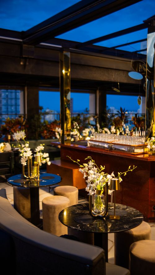 Free Elegant evening rooftop bar setting adorned with white orchid floral arrangements, offering a sophisticated ambiance. Stock Photo