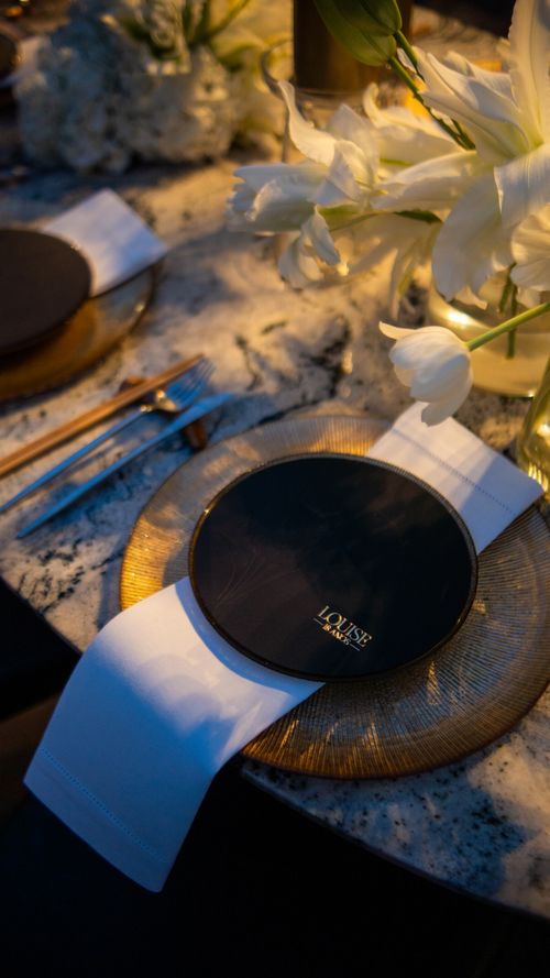 Free Sophisticated dinner table setup with flowers and elegant dishware under warm light. Stock Photo
