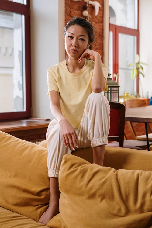 Woman in White Crew Neck T-shirt Sitting on Brown Wooden Chair