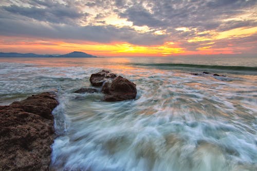 Laut Di Bawah Awan Putih Saat Matahari Terbenam Oranye