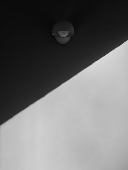 From below of black and white wall of contemporary style house with straight line representing day and night under hanging street lamp with rounded bulb
