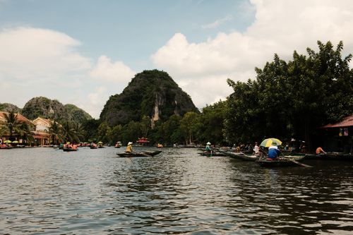 Free A picturesque river scene with limestone mountains, boats, and lush greenery under a bright sky. Stock Photo