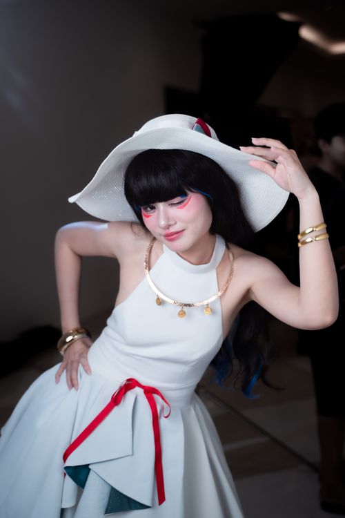 Free Fashionable woman in white dress and hat posing indoors with a vibrant makeup look. Stock Photo
