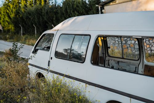 Free An abandoned white van sits in overgrown grass in Gölbaşı, Ankara, capturing a scene of decay and urban exploration. Stock Photo