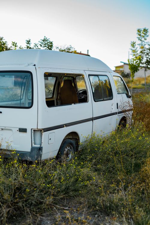 Free An old, abandoned white van sits amidst overgrown grass and wildflowers in Gölbaşı, Ankara. Stock Photo