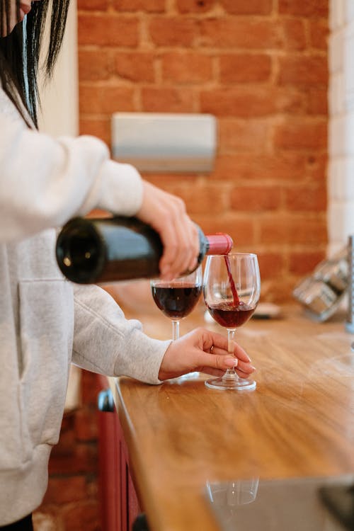 Person in White Long Sleeve Shirt Holding Wine Bottle