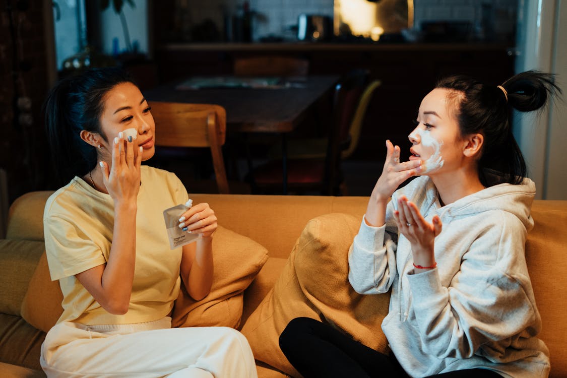 Free Woman in White Sweater and Black Pants Sitting on Brown Couch Stock Photo