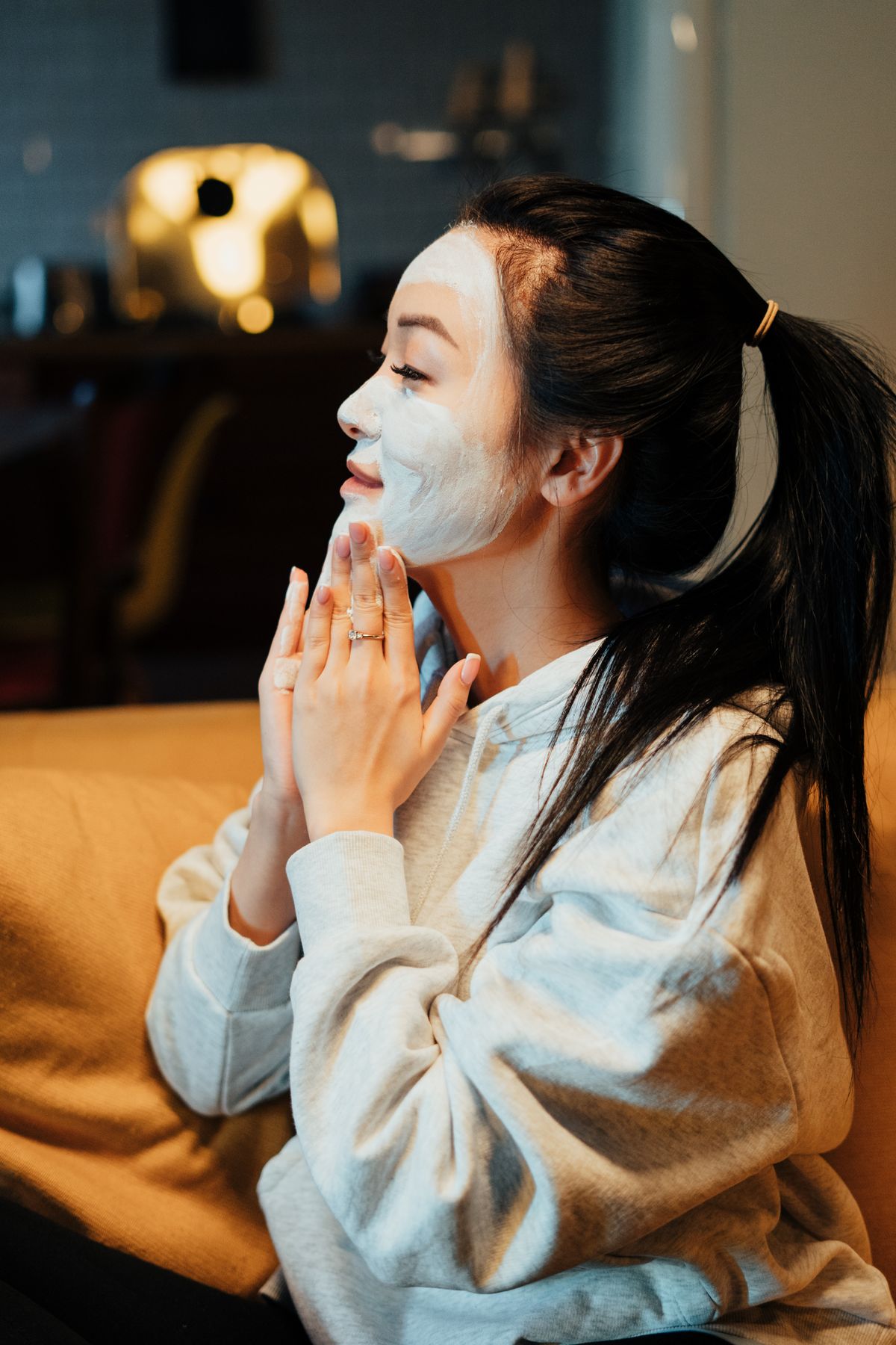 Chica asiática relajándose en casa con una mascarilla facial en una noche de cuidado de la piel