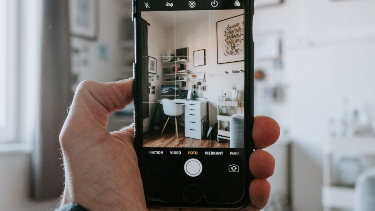 Main tenant un smartphone qui photographie un interieur