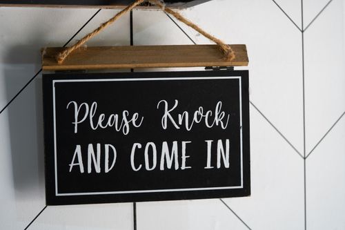 Free A black, wooden door sign reading please knock and come in. Stock Photo
