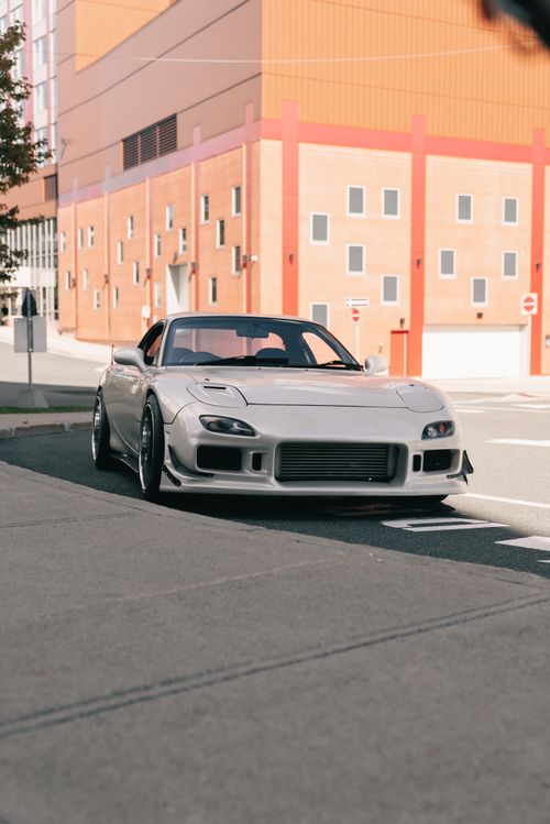 Free A stylish white sports car parked on an urban street in daylight, emphasizing modern urban lifestyle. Stock Photo
