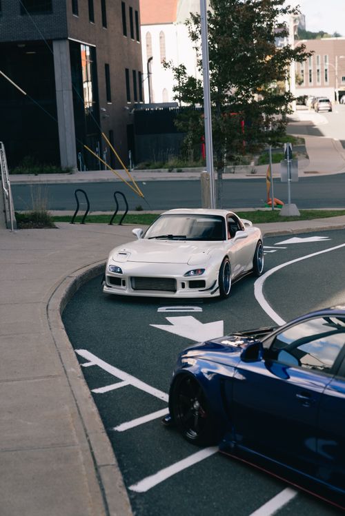 Free Two sleek sports cars navigating an urban street under daylight. Stock Photo