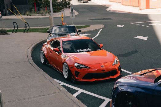 A striking orange sports car parked on an urban street during the day.
