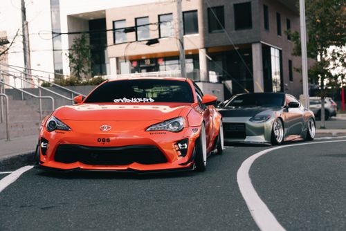 Free Custom-modified Toyota and Nissan sports cars parked on a city street, highlighted in an urban setting. Stock Photo