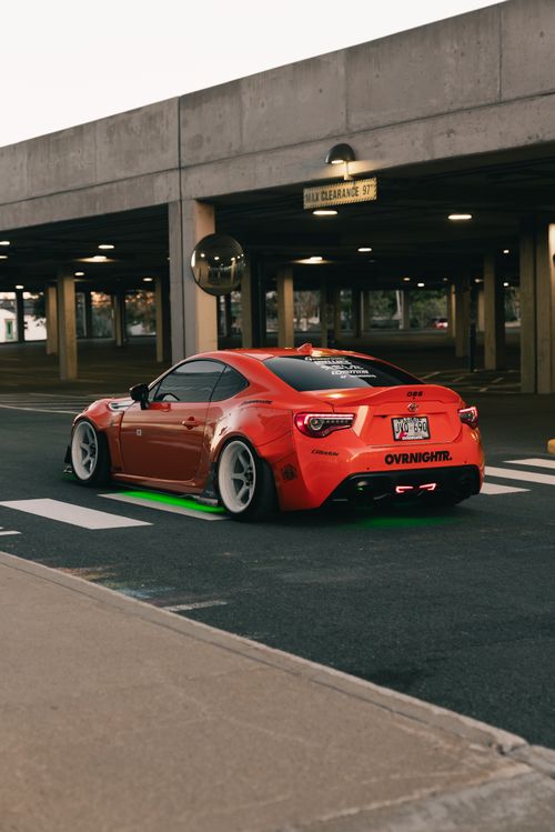 Free Dynamic shot of a red sports car with custom lights in an urban environment at dusk. Stock Photo