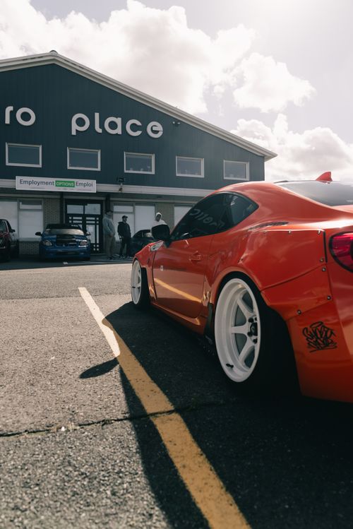 Free Vibrant red sports car parked near an employment center on a sunny day. Stock Photo