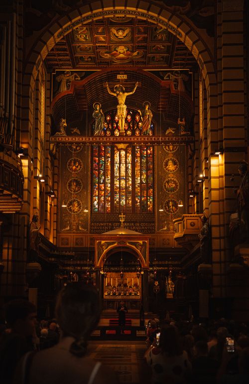 Free Beautifully lit interior of a grand cathedral featuring stained glass and wooden altar. Stock Photo