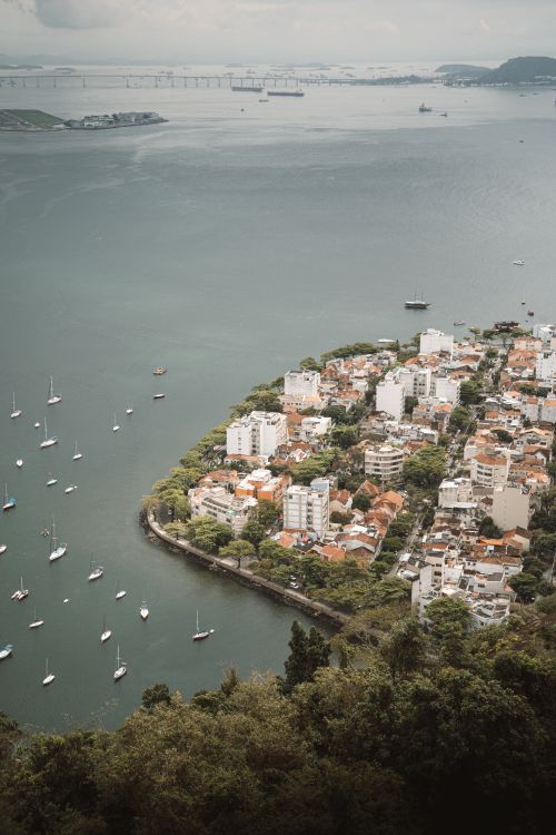 Free A serene aerial view of a coastal city with boats docked, captured from above. Stock Photo