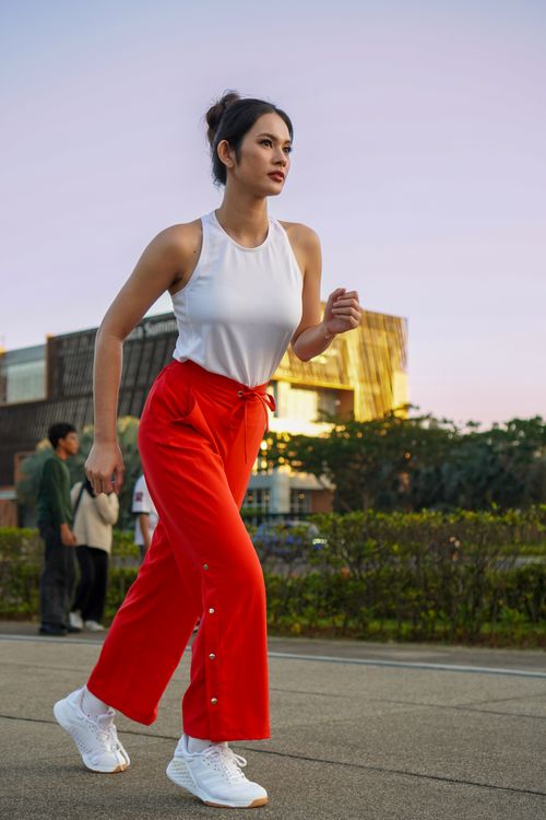 Free Confident young woman walking outside, enjoying a daytime stroll in stylish red pants. Stock Photo