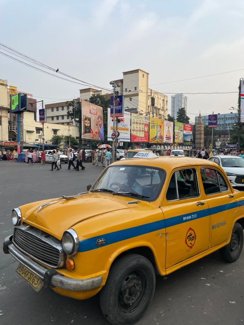Free Yellow taxi on a bustling street in Kolkata, India, showcasing urban life and classic vehicles. Stock Photo