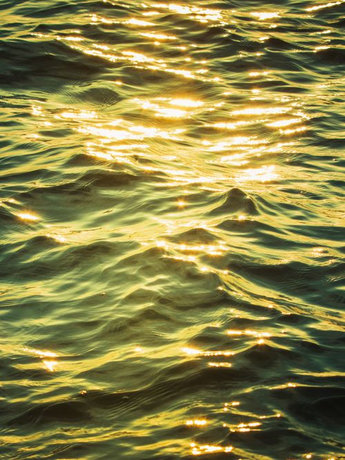 Free Captivating view of sunlight reflecting on ocean waves, creating a golden shimmer. Stock Photo