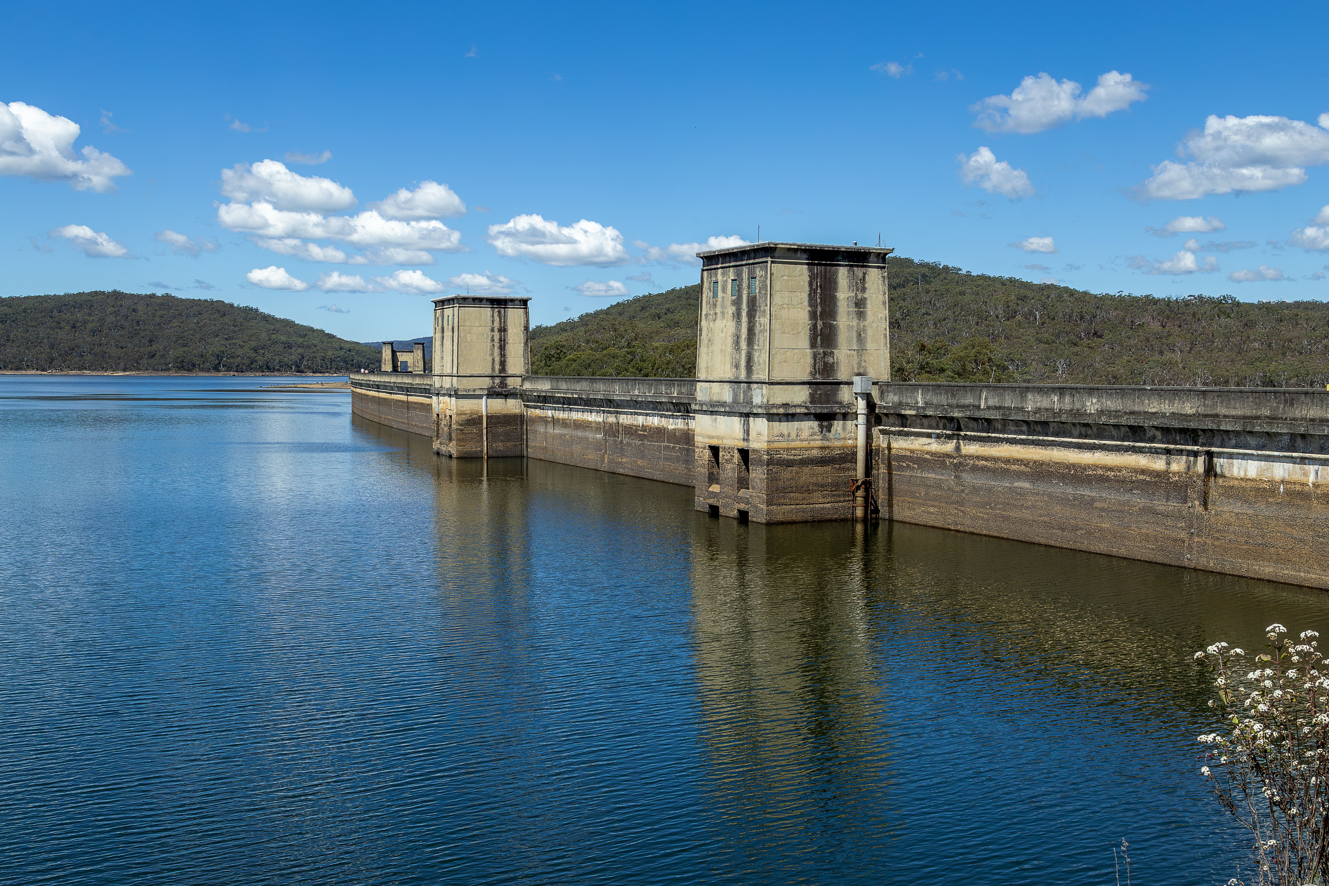 A tranquil view of Cordeaux Dam with clear blue skies and reflections in New South Wales, Australia.
