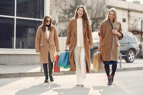 Happy women walking with paper bags after shopping