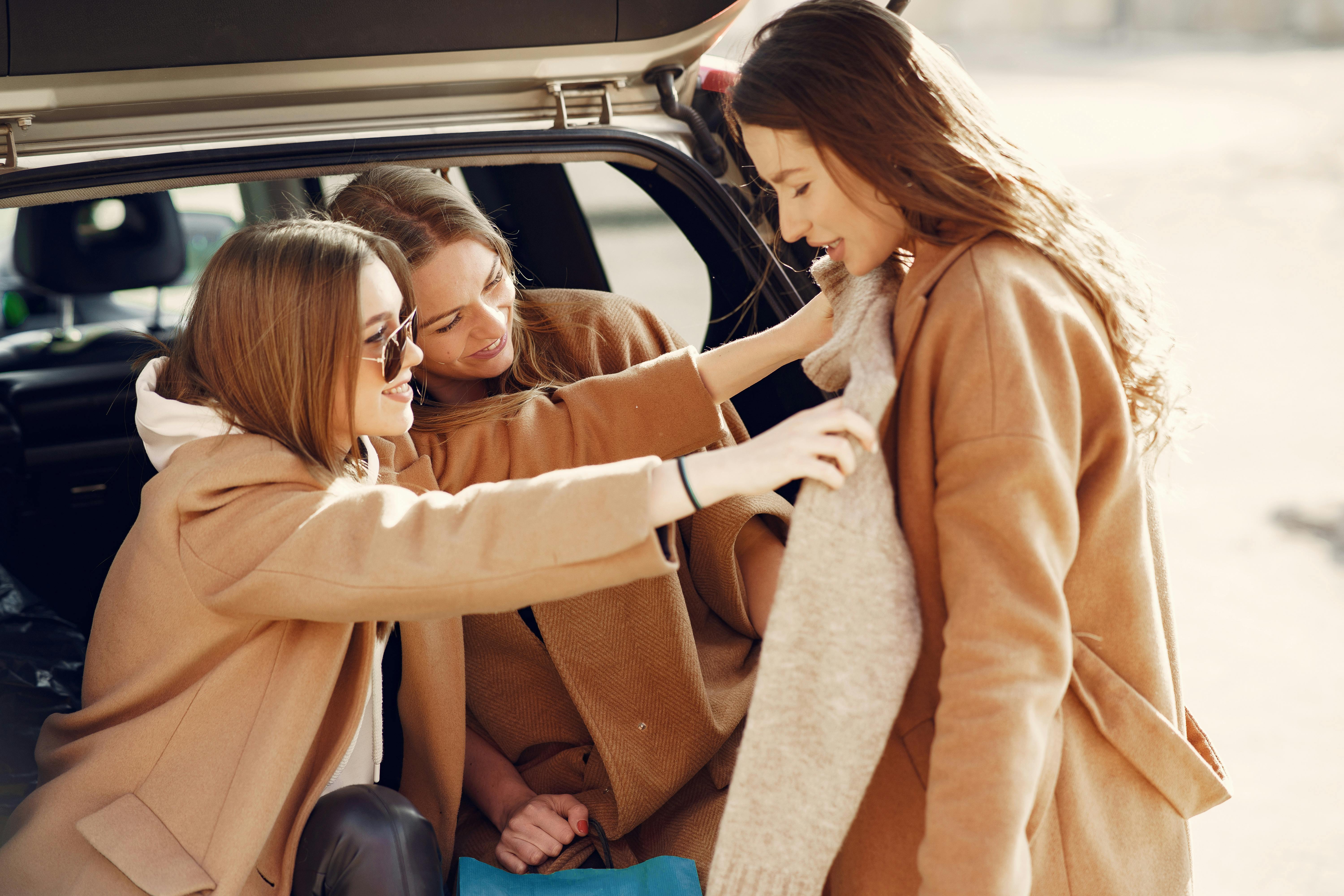 smiling young women checking new sweater of friend