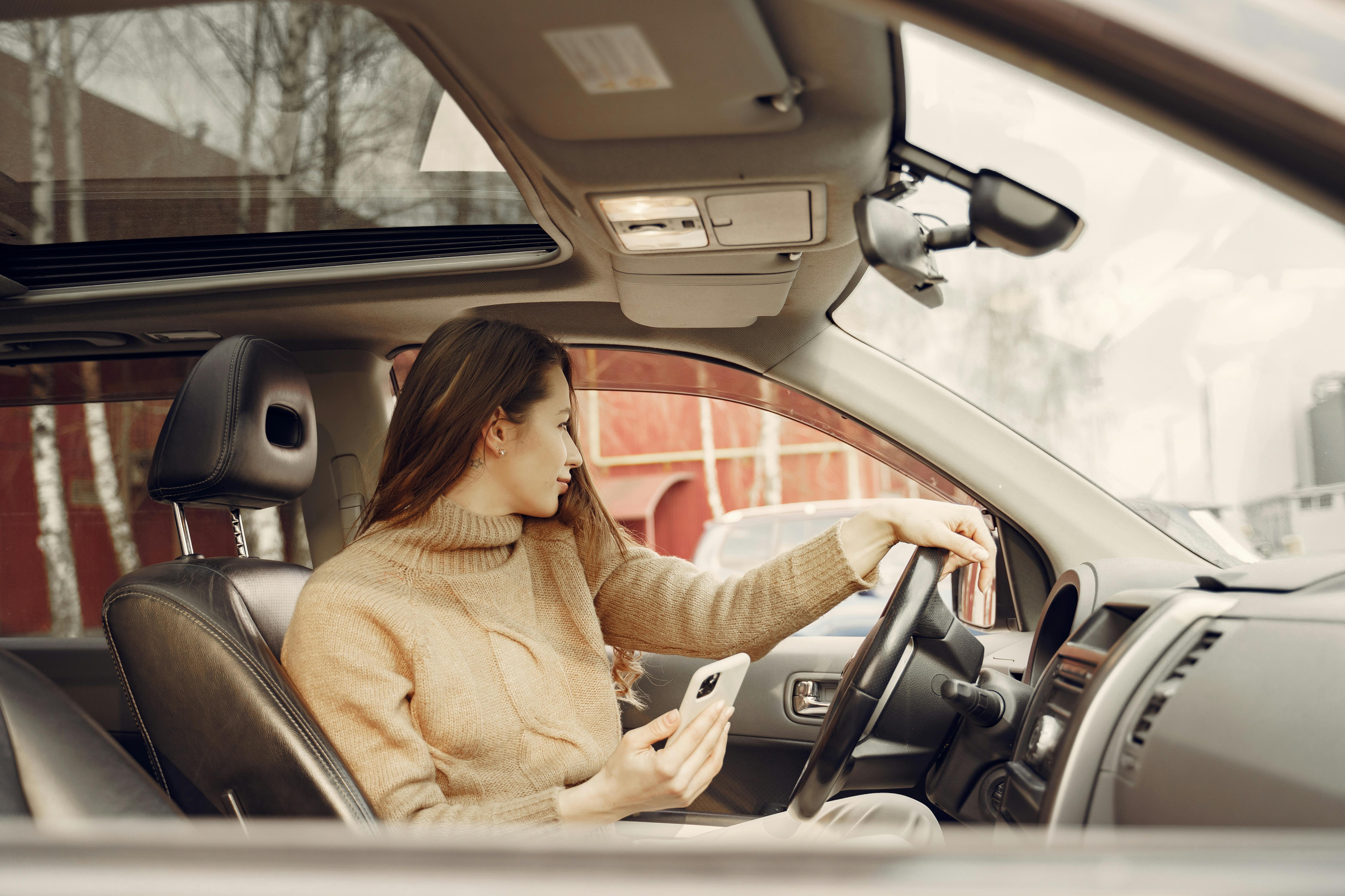 Adult woman sitting in car and using smartphone · Free Stock Photo