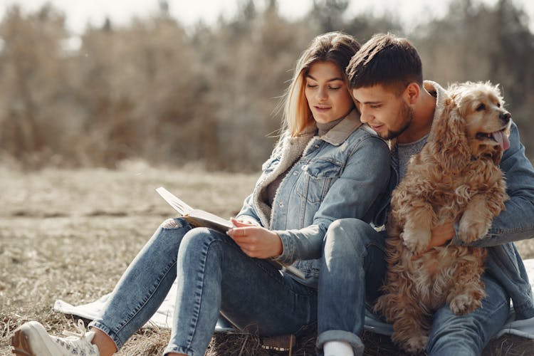 Happy Couple Looking At Photo Album On Lawn