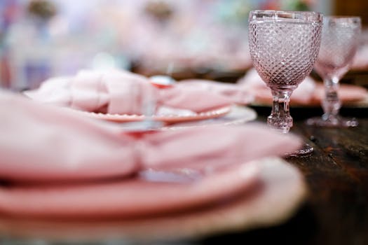 Delicate table setting featuring crystal wine glasses and soft pink napkins, capturing sophistication.