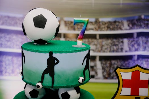 A two-tiered soccer-themed cake with a rainbow number seven candle, perfect for a football fan's birthday.