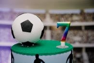 这款足球主题蛋糕，配有足球装饰和色彩缤纷的七号蜡烛，非常适合体育主题的生日庆祝活动