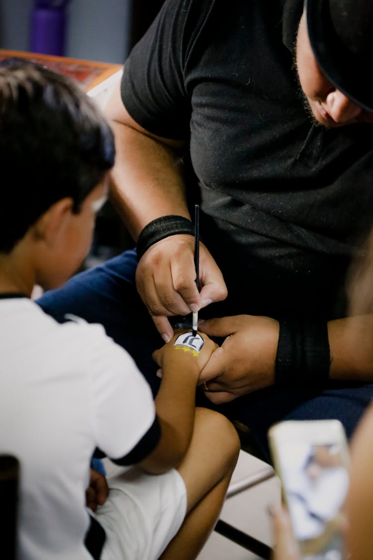 Crop Master Painting Football Team Emblem On Hand Of Boy