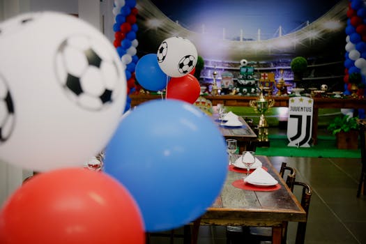 Colorful football party setup indoors with balloons and table settings, perfect for sports enthusiasts.