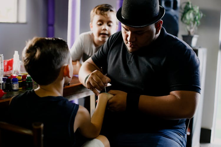 Male Artist Painting On Hand Of Boy In Art Studio