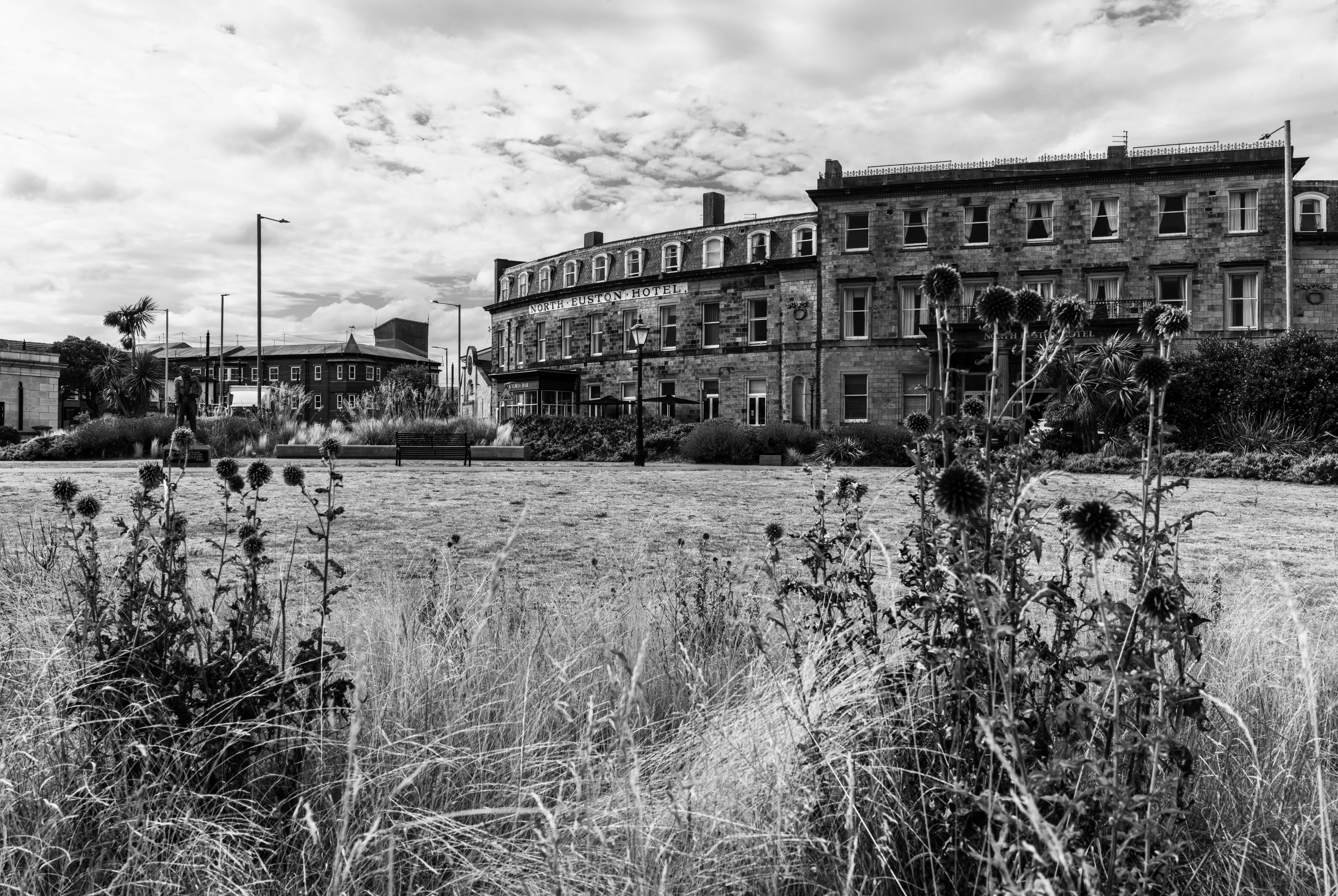 Black and white view of historic hotel and garden in Blackpool, England, featuring rustic architecture and overcast skies.