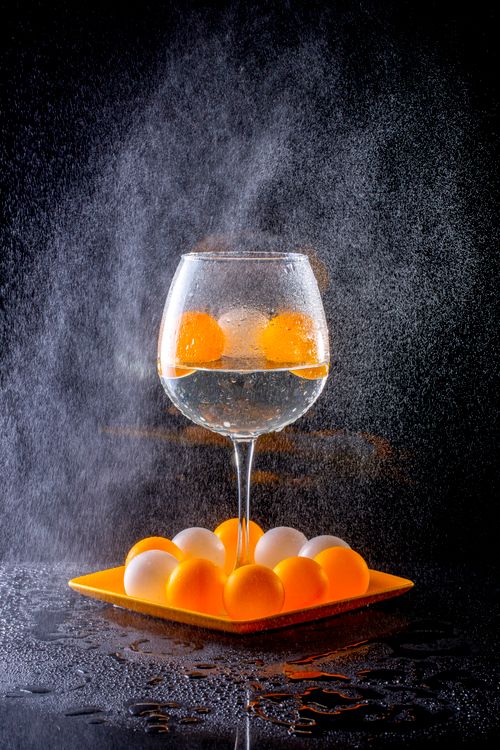 Free Artistic still life of a wine glass with oranges and spray effect on dark background. Stock Photo