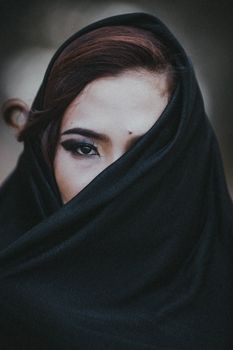 这是一张戴着黑色头巾的女子的特写肖像，突出了她的眼睛