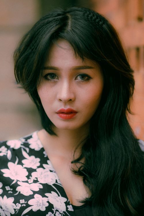 Free Close-up portrait of a woman with long black hair, red lips, and floral attire. Stock Photo