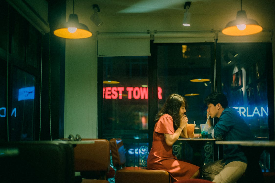 Asian couple drinking cocktails in cafe at night