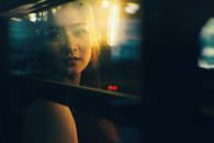 夜晚，一名女子透过公交车窗凝视，车窗映出温暖的反光