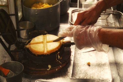 Free Hands of a vendor preparing waffles on a street food stall with traditional waffle iron. Stock Photo